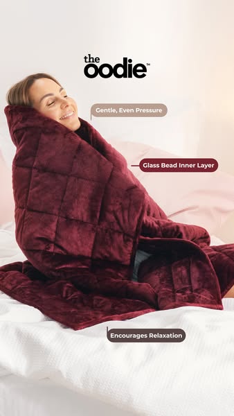 This ad features a woman relaxing comfortably under The Oodie weighted blanket. The ad highlights the blanket's gent
