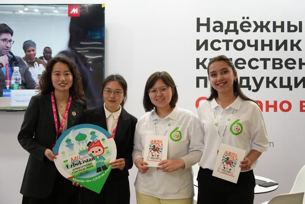 This image ad features four young women at a trade show, promoting MIC(Made-in-China) Uzbekistan. They are posing in fro