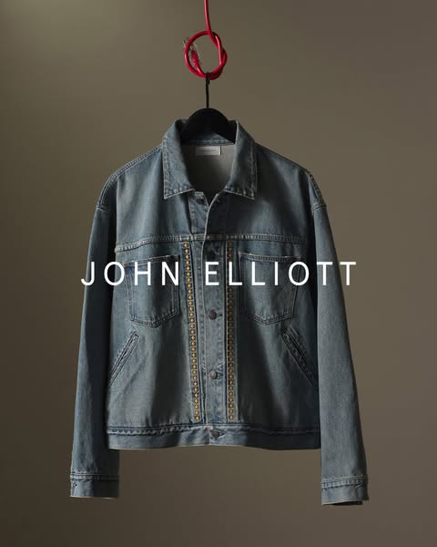 This ad features a John Elliott denim jacket hanging against a neutral background. The brand name is prominently display