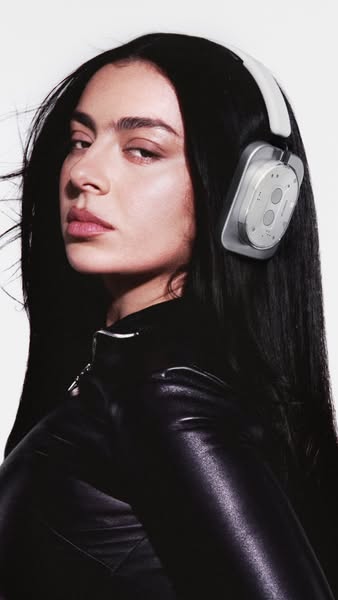 This image features a celebrity wearing wireless headphones. The image is cropped from the shoulders up and features the