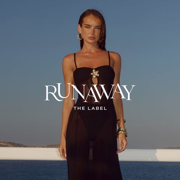 This image ad features a model wearing an outfit from Runaway The Label against a background of blue sky and ocean. The 