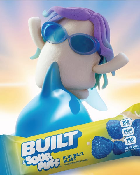 This image ad promotes Built Sour Puff protein bars. It features a whimsical character holding the Blue Razz Blast bar, 