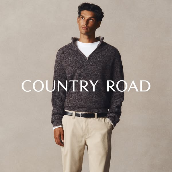 A photo showcases a man wearing a Country Road sweater, layered over a white t-shirt, paired with khaki pants. The backg