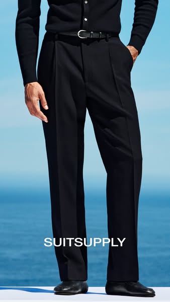 This ad by Suitsupply showcases their pleated navy blue trousers as part of a coordinated outfit. The focus is on the tr