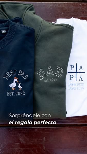 The image ad displays three garments: a navy blue sweater with a duckling design, an olive green hoodie with the word &q