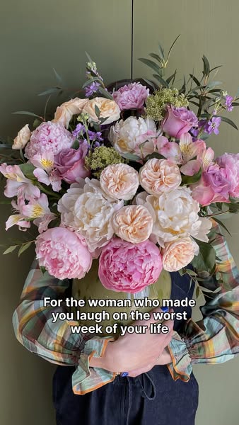 This image ad features a person holding a large bouquet of flowers in front of an olive green wall. The on-screen text r