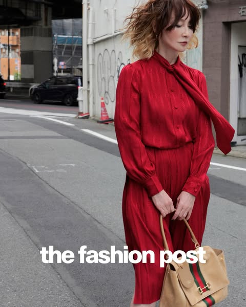 A street-style shot featuring a woman wearing a red dress and carrying a beige handbag. The ad is advertising "the 