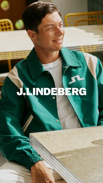 This image ad showcases a stylish green J.Lindeberg jacket. A man is seen sitting at a table wearing the jacket. The bra