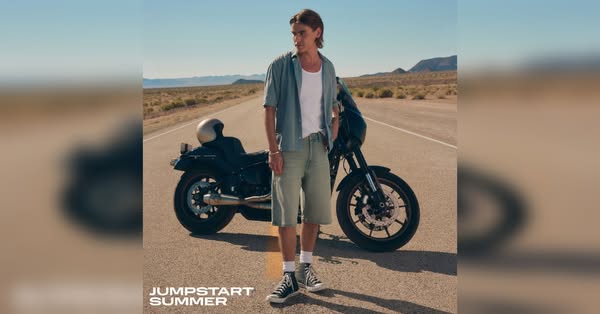 This ad features a man standing in front of a motorcycle in a desert landscape, wearing a casual outfit that highlights 