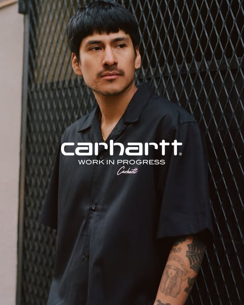 This ad features a medium shot of a man wearing a black Carhartt button-up shirt. The Carhartt logo is featured prominen