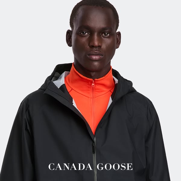 A close-up shot of a man wearing a black Canada Goose rain jacket, drawing attention to the brand and showcasing the jac