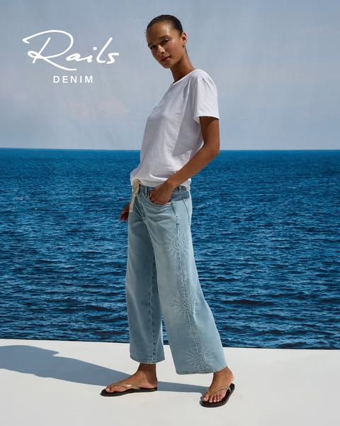 An ad for Rails denim featuring a woman in a white t-shirt and the brand's light-wash, wide-leg jeans with sunburst 
