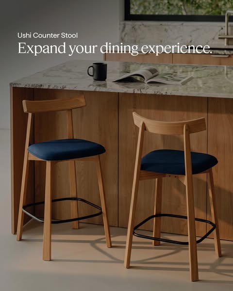 The ad showcases two wooden counter stools with blue cushions, set in a modern kitchen setting. The stools are presented