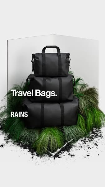 This image ad showcases a stack of three RAINS travel bags, arranged in a minimalist setting with natural and architectu