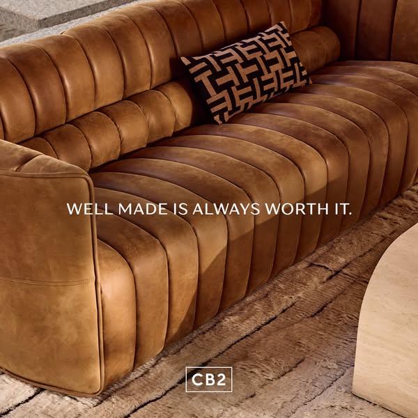 This ad for CB2 features a close-up shot of a brown leather couch with a patterned pillow. The ad emphasizes the quality