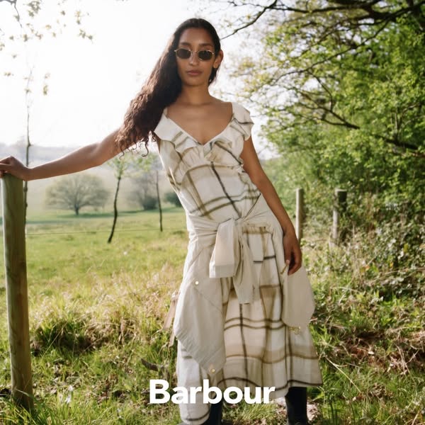 This ad features a woman in a field of grass modeling a plaid Barbour dress. The ad has a natural, outdoorsy feel.