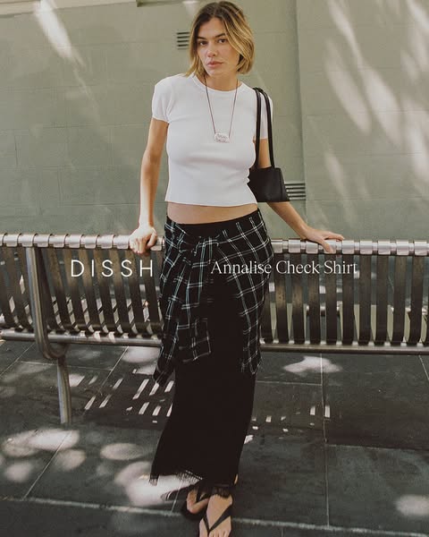 This ad features a stylish woman wearing a casual outfit from DISSH. The outfit includes a white t-shirt, a black midi s
