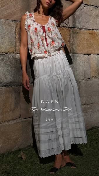This ad displays a woman leaning against a brick wall while modeling Doen's The Sebastiane Skirt.