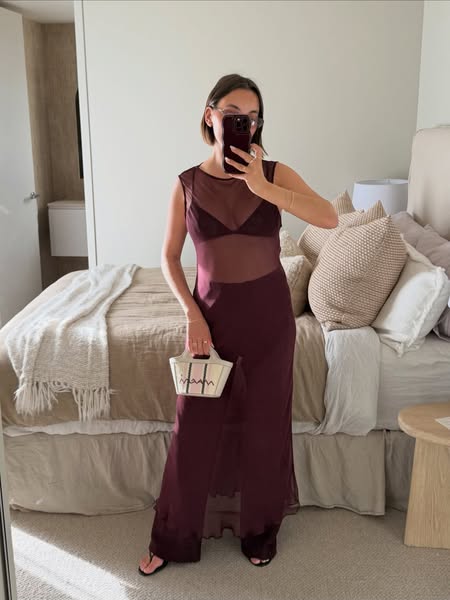 This ad is an image of a woman taking a mirror selfie wearing a sheer dress and holding a bag.