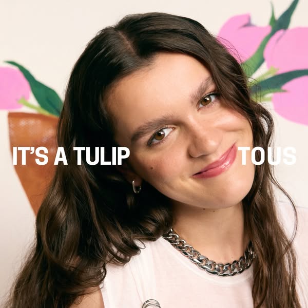 This ad features a person modeling a silver chain necklace while standing in front of a floral background. The ad is sim