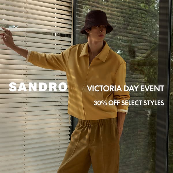 This ad for Sandro features a male model wearing Sandro apparel, including a yellow jacket, pants, and a bucket hat. The