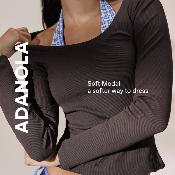 This image ad features a woman wearing a long-sleeved brown shirt from ADANOLA. The ad highlights the softness of the mo