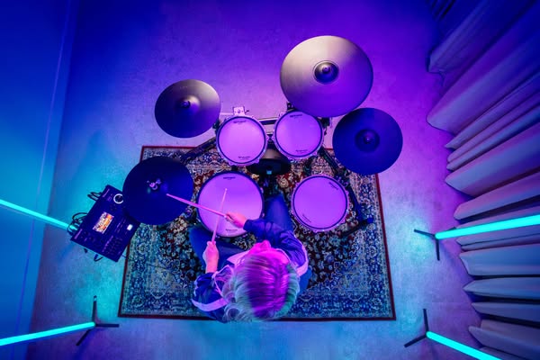 This ad features an overhead shot of a person playing an electronic drum set in a room with blue lighting. The ad is lik