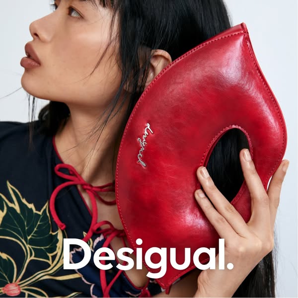 An ad for Desigual showcasing a red purse. The ad features a woman holding the product and the Desigual logo is displaye