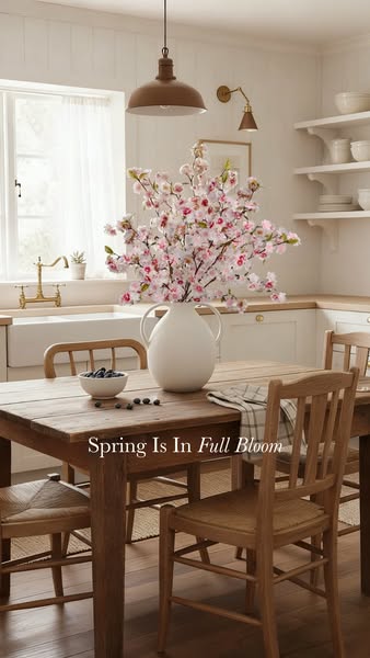 This image ad showcases a neutral-toned kitchen with spring blossoms in a white vase, advertising seasonal decor.