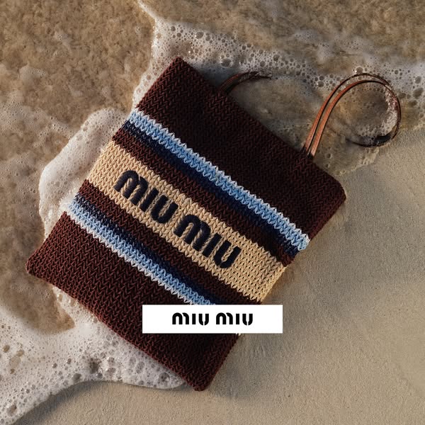 This ad showcases a Miu Miu handbag on a beach, partially submerged in water.