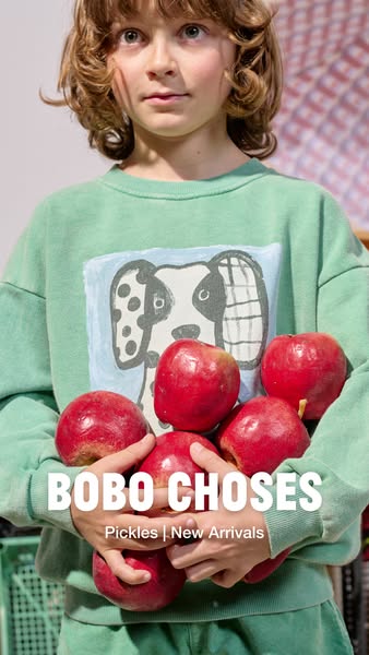 This ad for Bobo Choses features a young child holding a collection of red apples and draws attention to the brand's