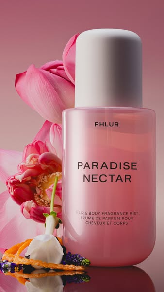 This image ad features a pink bottle of PHLUR Paradise Nectar hair and body fragrance mist, surrounded by lotus flowers 