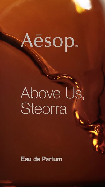 This ad features a close-up shot of an Aesop Eau de Parfum bottle, highlighting the brand and product name against a bac