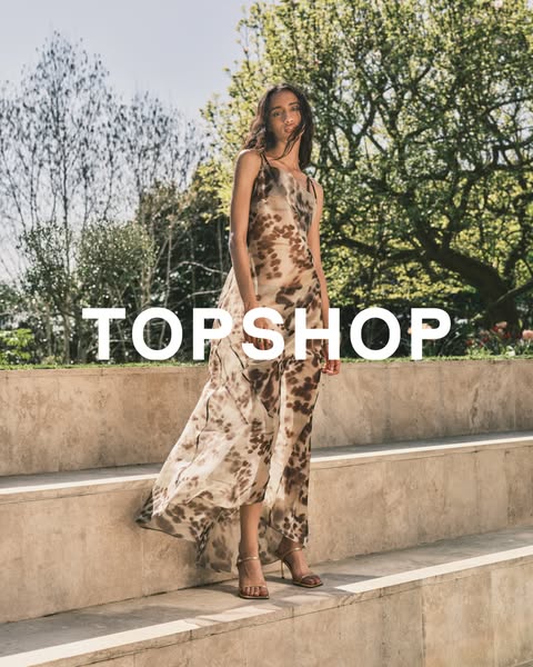 This ad for Topshop features a woman in a long dress with a pattern, standing on stairs in an outdoor setting. The brand