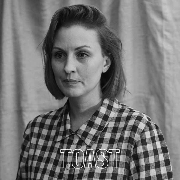 This ad features a black and white photo of a woman wearing a black and white checked shirt with the word "TOAST&qu