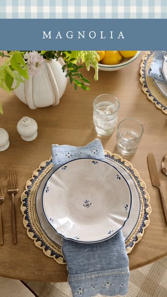 This ad showcases Magnolia brand dining ware. The image depicts a table setting with neutral colored plates, blue floral