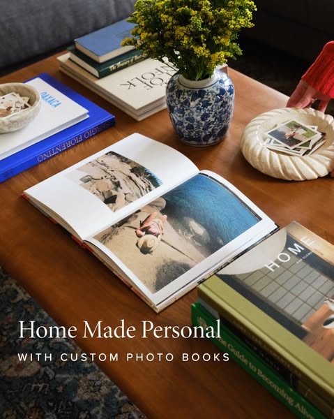 The ad showcases custom photo books in a cozy, home setting, inviting viewers to create personalized keepsakes.