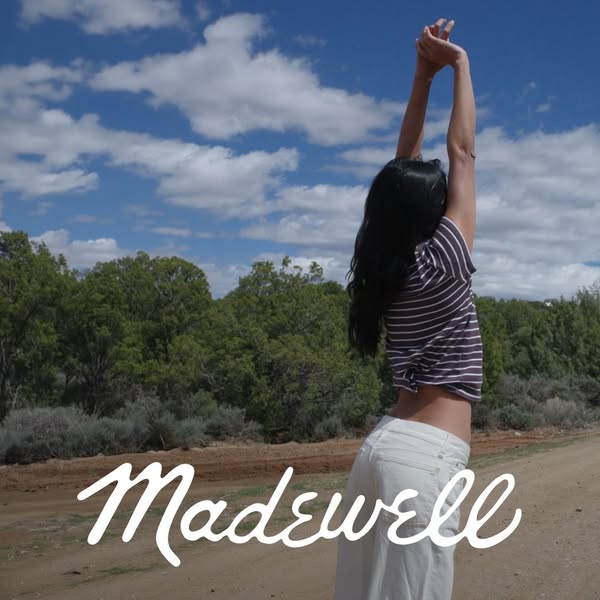 This ad features a woman standing in a natural outdoor setting, wearing Madewell clothing. The image emphasizes the bran