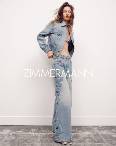 A woman models Zimmermann brand denim jacket and jeans.
