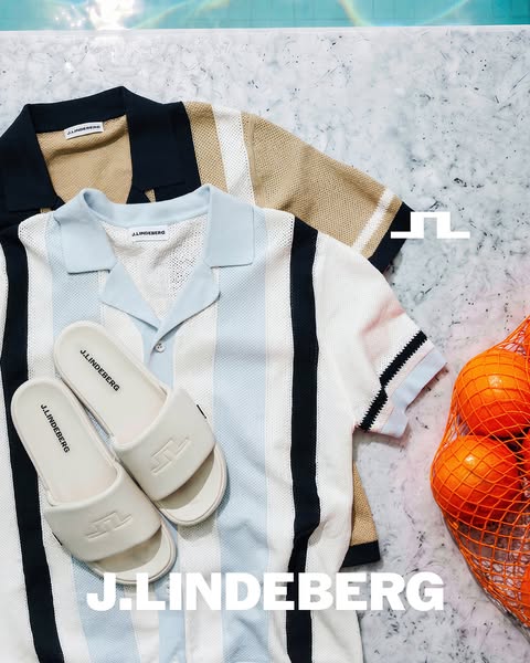 This image showcases clothing and shoe products from J.Lindeberg, presented on a marble surface with an orange mesh bag.