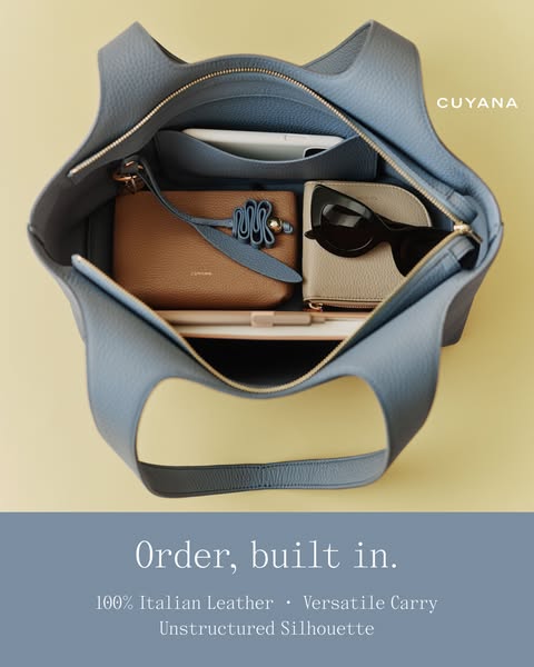This ad showcases a Cuyana tote bag in a high-angle, flat lay-style shot. The bag is presented as organized and spacious