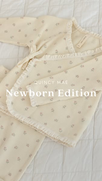 The ad features a cream-colored, long-sleeve pajama set with a floral pattern, showcased on a white quilted blanket. The