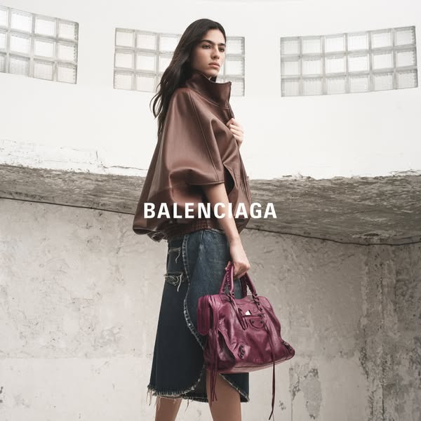 This image ad showcases a woman with a Balenciaga handbag and jacket. The shot is framed to focus on the Balenciaga bran