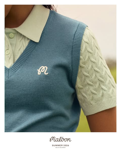 An eye-level close-up shot of a person wearing a mint-green collared shirt with a blue sweater vest. In the lower center