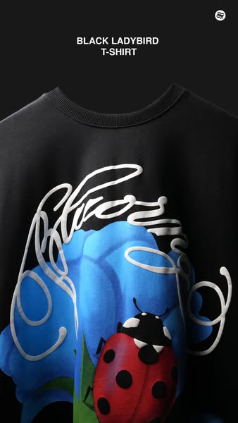 This ad features a close up of a black t-shirt with a blue flower and ladybug design on the front. The product name is s