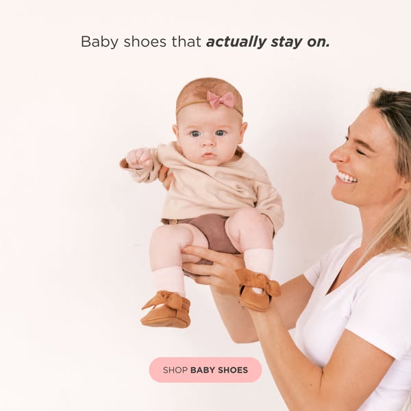 This image ad features a baby wearing brown baby shoes. The mother is holding the baby up and she is smiling. The text i