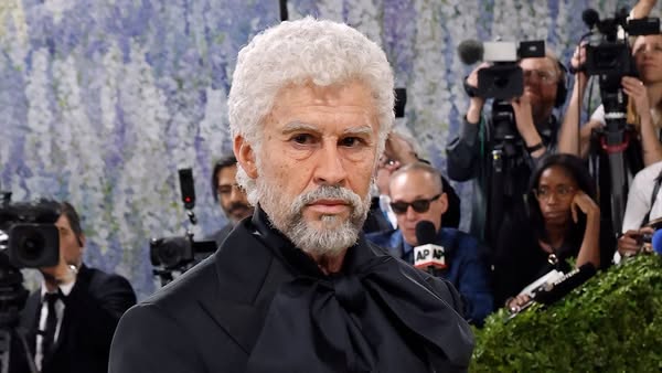 This ad features a high-profile man at what appears to be a formal event, likely a fashion show, with a crowd of photogr