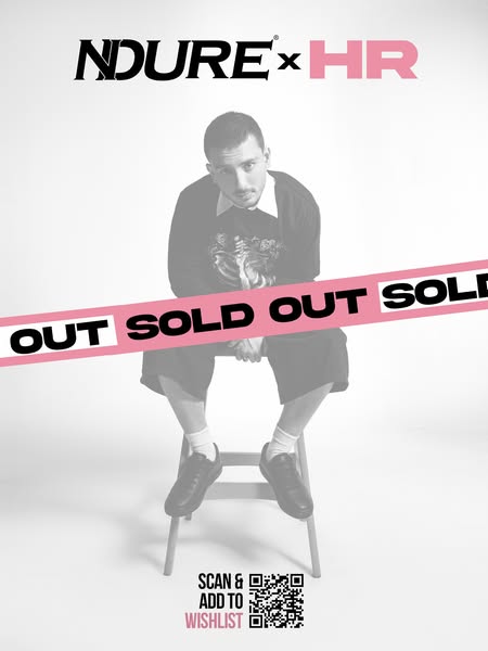 This is an image ad for NDURE shoes and features a man sitting on a stool wearing black shoes. A pink bar runs across th