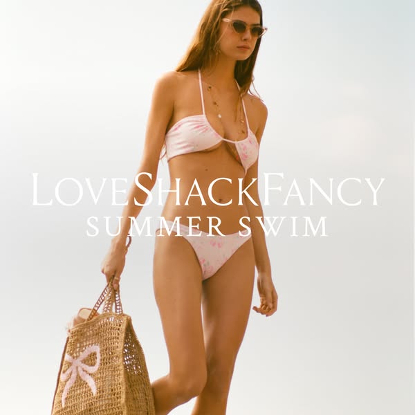 This ad features a model wearing a LoveShackFancy swimsuit and carrying a woven bag. The ad promotes LoveShackFancy'