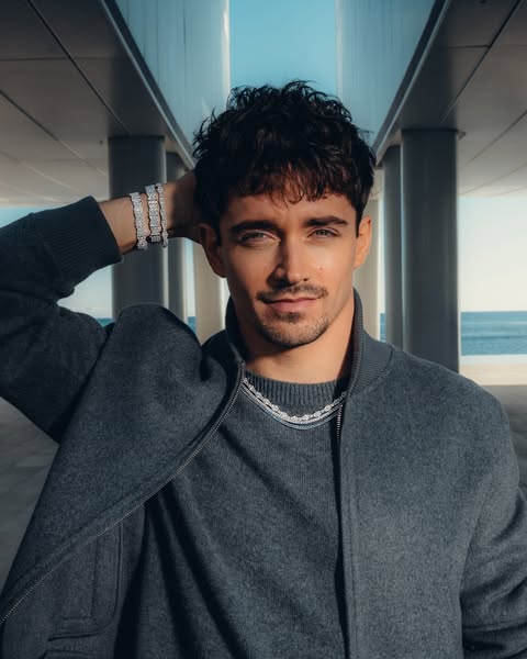 This ad features Charles Leclerc wearing several diamond bracelets and necklace, set against a modern, coastal backdrop.